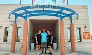 Indgangen til bygningen med skilte og flag ovenover. (AI-genereret tekst)