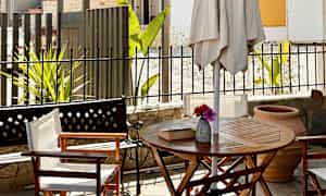 En terrasse med bord, stole og parasol. (AI-genereret tekst)