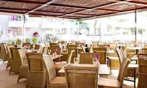 Restaurant med fletmøbler og blomster på bordene. (AI-genereret tekst)