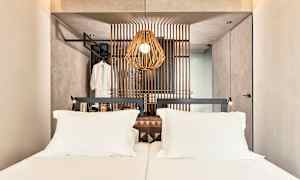 Et hotelværelse med en dobbeltseng og en dekorativ træpanel bag sengen. (AI-genereret tekst)