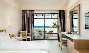 Hotelværelse med seng, skrivebord og altan med havudsigt. (AI-genereret tekst)