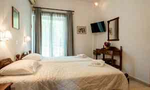 Et hotelværelse med to enkeltsenge, et tv, et vindue med gardiner og et træbord med et spejl. (AI-genereret tekst)