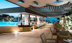 Restaurant med udsigt til en pool og udendørsområde med havudsigt om aftenen. (AI-genereret tekst)