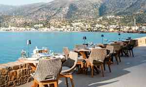 Udendørs servering ved havet med udsigt over bjergene og en by. (AI-genereret tekst)