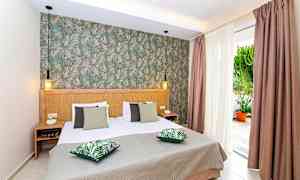 Soveværelse med dobbeltseng, grønne puder og dekoreret væg. (AI-genereret tekst)