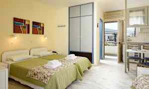 To senge med grønt sengetøj og blomstrede sengeoverkast i et rum med skab, køkkenbord og dør til altan. (AI-genereret tekst)