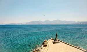 En stenstrand og hav med et kunstværk synligt på en mole. (AI-genereret tekst)