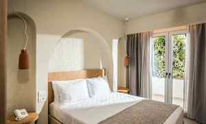 Et hotelværelse med en dobbeltseng, natbord og vindue med gardiner. (AI-genereret tekst)