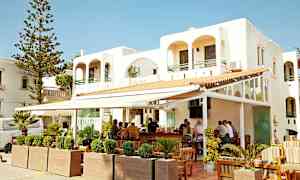 Hvid bygning med udendørs bar og siddepladser. (AI-genereret tekst)