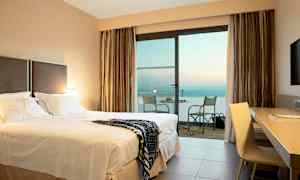 Hotelværelse med dobbeltseng og altan med havudsigt. (AI-genereret tekst)