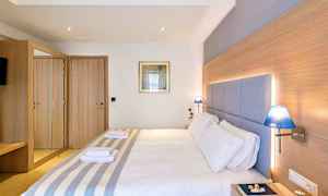 Et hotelværelse med en dobbeltseng, trædetaljer, blå lamper og et spejlskab. (AI-genereret tekst)