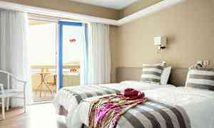 Et hotelværelse med to enkeltsenge, stribet sengetøj og en dør til en altan. (AI-genereret tekst)