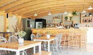 En cafeteria med træinteriør, borde, stole og en bardisk. (AI-genereret tekst)