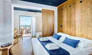 Lyst hotelværelse med dobbeltseng og trædetaljer, udsigt til balkon og hav. (AI-genereret tekst)