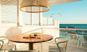 Udendørsområde med et bord og stole, havudsigt i baggrunden. (AI-genereret tekst)