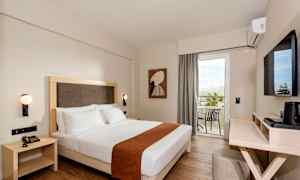 Hotelværelse med en dobbeltseng, vægmonterede lamper og en balkon med udsigt. (AI-genereret tekst)