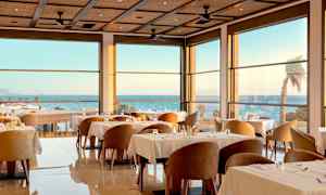 En elegant indendørs restaurant med store vinduer og havudsigt. (AI-genereret tekst)