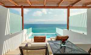 Udsigt over en terrasse med to liggestole, et bord og en privat pool, med havet i baggrunden. (AI-genereret tekst)