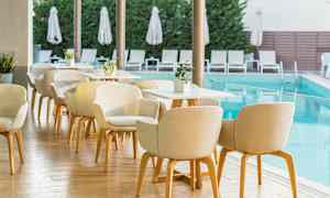 Udendørs servering ved pool med stole og borde. (AI-genereret tekst)