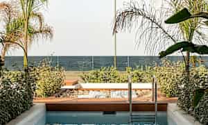 En lille pool med en træhave ved siden af, udsigt over havet og glasrækværk. (AI-genereret tekst)