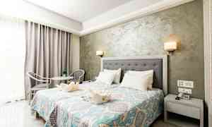 Et hotelværelse med dobbeltseng, natbord, dekorativt sengetæppe og siddegruppe. (AI-genereret tekst)