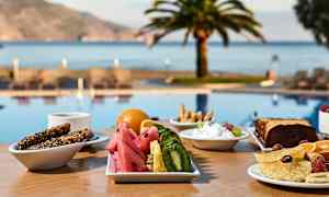 En morgenmad serveres på et bord tæt på en pool med udsigt over havet og palmer. (AI-genereret tekst)