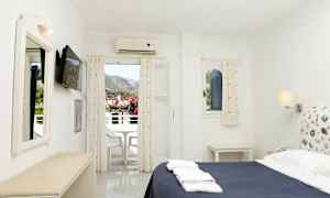 Et hotelværelse med en seng, et tv på væggen og en altan med udsigt over bjergene. (AI-genereret tekst)