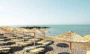 En strand med solsenge og parasoller foran et roligt hav. (AI-genereret tekst)