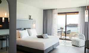 Hotelværelse med dobbeltseng, siddeområde og udsigt over havet. (AI-genereret tekst)