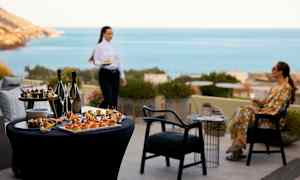 Bord med forretter og drikkevarer, i baggrunden havudsigt. (AI-genereret tekst)