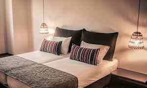 Et soveværelse med en dobbeltseng, pyntesofapuder og hængende lamper. (AI-genereret tekst)