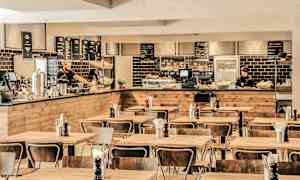 Spiseområde med træmøbler og en serveringsdisk i baggrunden. (AI-genereret tekst)