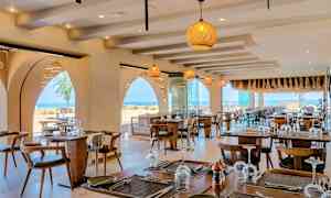 Restaurant med dækkede borde og havudsigt. (AI-genereret tekst)