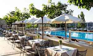 Billede af en udendørs swimmingpool med liggestole og hvide parasoller, omgivet af borde og stole under små træer. (AI-genereret tekst)