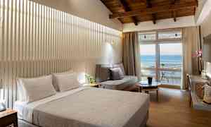 Hotelværelse med dobbeltseng, sofa og altan med havudsigt. (AI-genereret tekst)