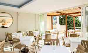 Restaurant med spiseborde og stole, udsigt til en terrasse. (AI-genereret tekst)