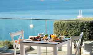 Et dækket bord med forskellige retter og udsigt over havet. (AI-genereret tekst)