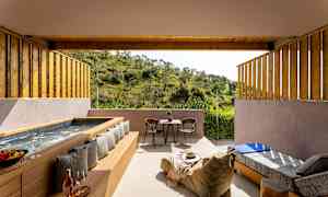 En gårdhave med badekar, siddepladser og udsigt til grøn natur. (AI-genereret tekst)