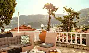 En terrasse med sofagruppe og udsigt over tage og bjerge. (AI-genereret tekst)