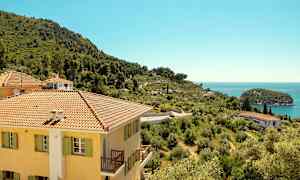 Bygning med gul facade og skrånende landskab med havudsigt. (AI-genereret tekst)