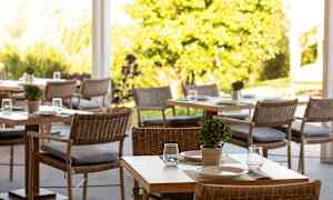 Et luftigt område med borde og stole, dekoreret med små planter og serveringsopstillinger. (AI-genereret tekst)