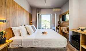 Hotelværelse med en dobbeltseng, udsmykket med træpaneler og en balkon med udsigt. (AI-genereret tekst)