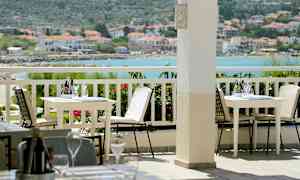 Udendørs terrasse med borde og stole, med havudsigt i baggrunden. (AI-genereret tekst)