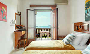 Et hotelværelse med to senge og en møbleret altan med udsigt over havet. (AI-genereret tekst)