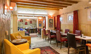 En restaurant med træbjælker i loftet og borde omgivet af røde og sorte stole. (AI-genereret tekst)