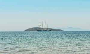 En sejlbåd på åbent vand med en ø i baggrunden. (AI-genereret tekst)