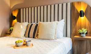 En oplyst seng med dekorative puder og en bakke med chips og drikke. (AI-genereret tekst)