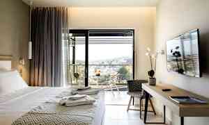 Hotelværelse med seng, TV, skrivebord og altan med udsigt. (AI-genereret tekst)