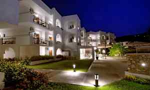 Hvid bygning med altaner, oplyst om natten. (AI-genereret tekst)