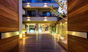 Indgang med træpaneler og belysning, der fører til en bygning med glasfacade. (AI-genereret tekst)